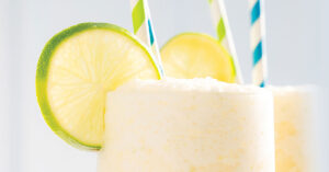 Lime Slushy drink with two straws and lime garnish